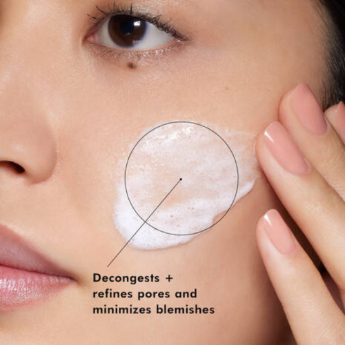 Close-up of a person applying a skincare product to their face with text indicating its benefits.
