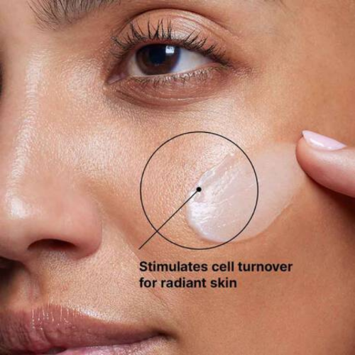Close-up of a woman's face with a product applied, labeled to stimulate cell turnover for radiant skin.