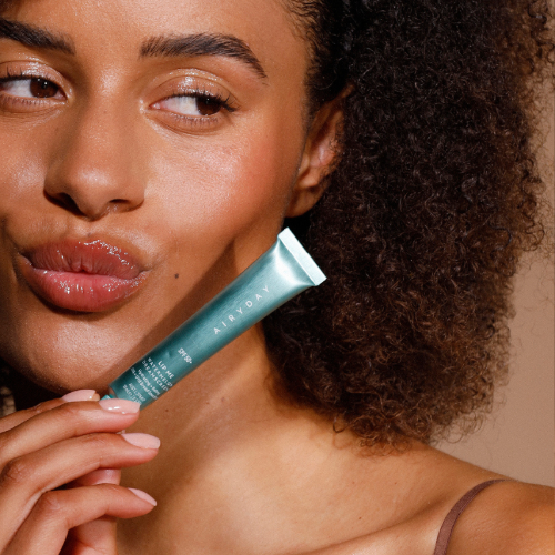 Woman holding a skincare product close to her face